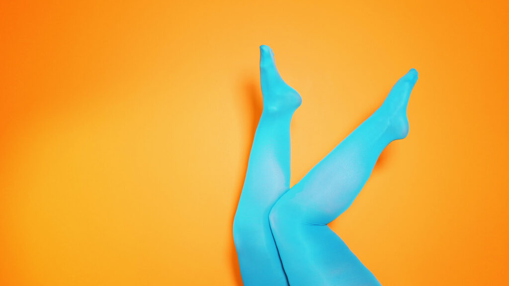 Beine mit blauen Kompressionsstrümpfen vor orangenem Hintergrund