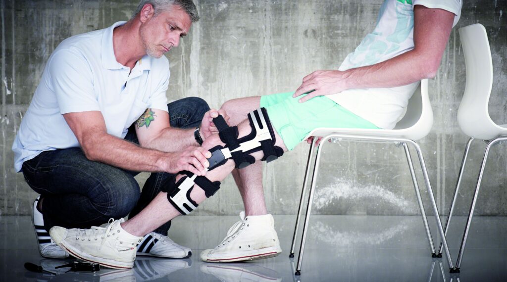 Orthopädietechniker legt dem Kunden eine Knieorthese an